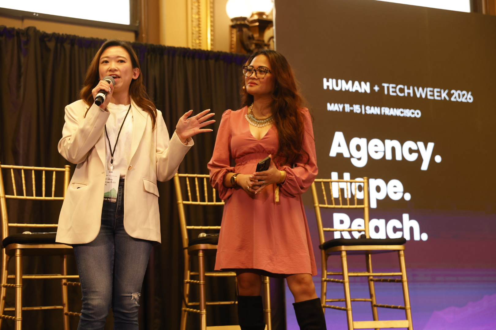 Two speakers on stage at the AGENCY summit beside a Human+Tech Week 2026 slide.