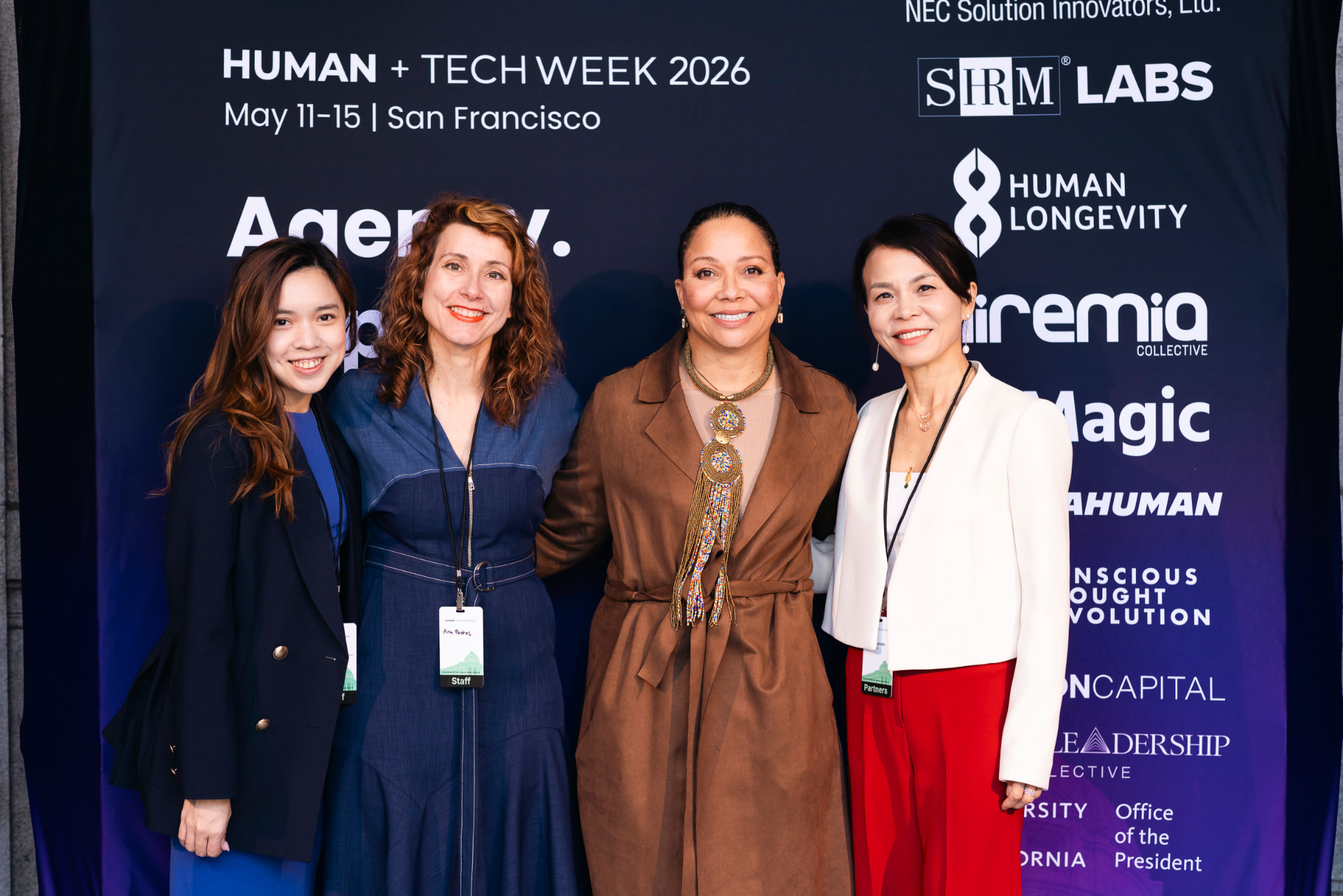 Four Human+Tech Week 2026 participants together at the San Francisco step-and-repeat.